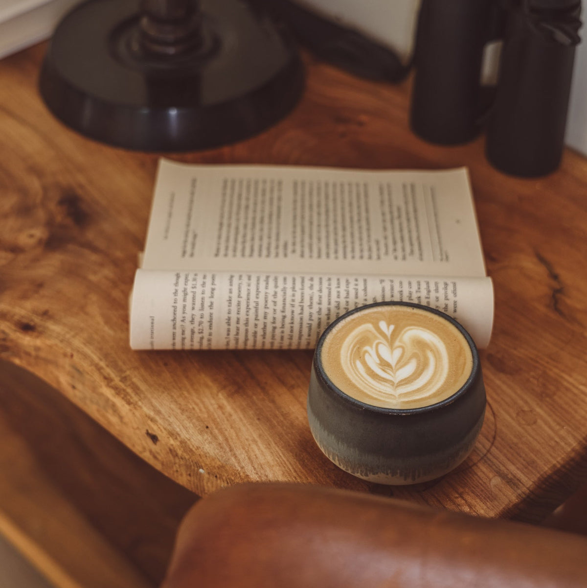 Flat white on a wooden table beside an open book