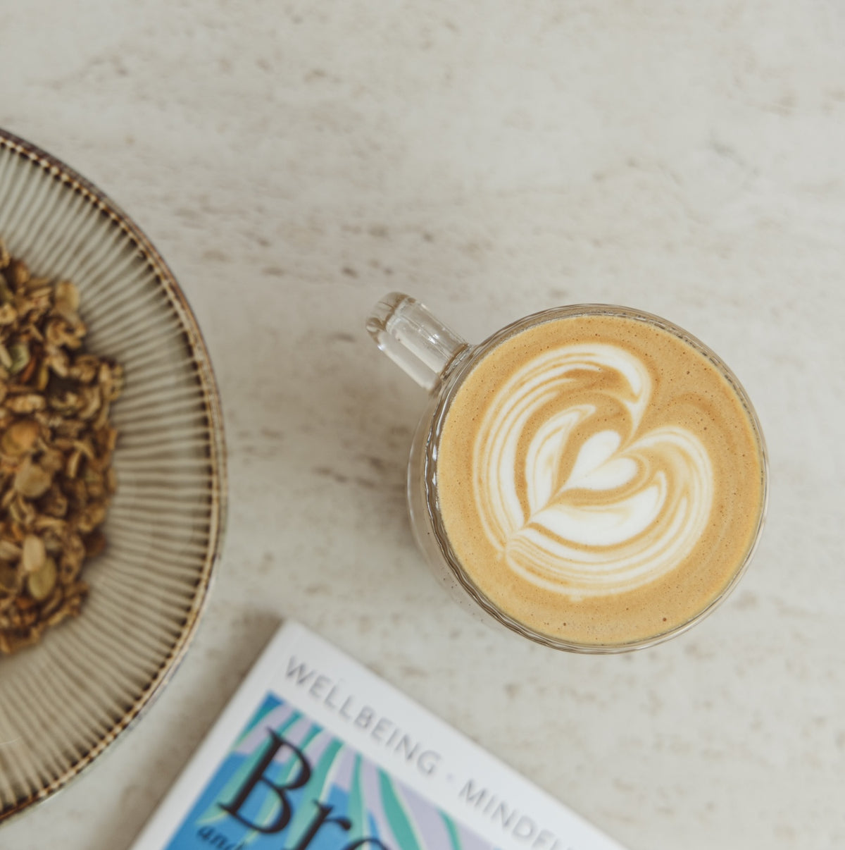 Latte with heart latte art next to a bowl of Pilgrims coffee beans